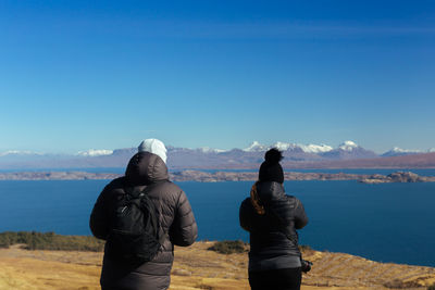 Rear view of couple looking at mountains against sky