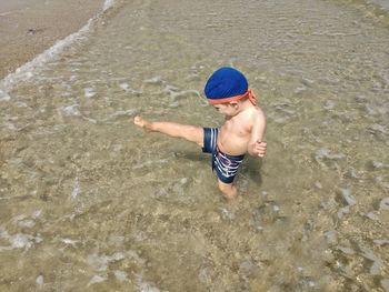 High angle view of boy kicking on shore