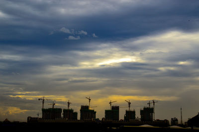 Silhouette of city against cloudy sky