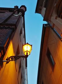 Low angle view of illuminated street light against buildings