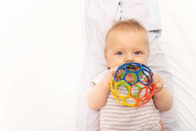 Portrait of cute baby girl holding toy against white background