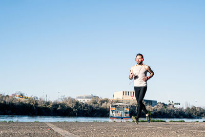 Full length of man running on road against clear sky