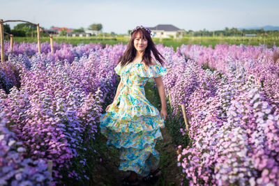 Portrait of woman with purple flowers on field