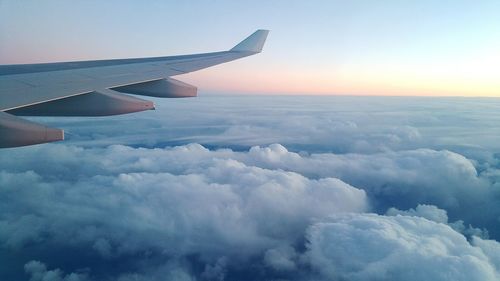 Cropped image of airplane flying over cloudscape during sunset