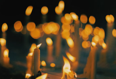 Close-up of lit candles in temple at night
