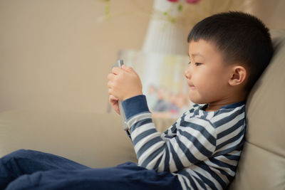 Close-up of boy looking away while relaxing on bed at home