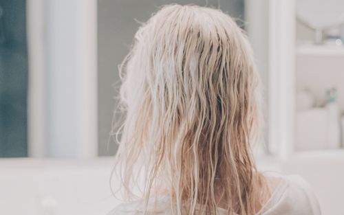 Rear view of woman with blond hair in bathroom