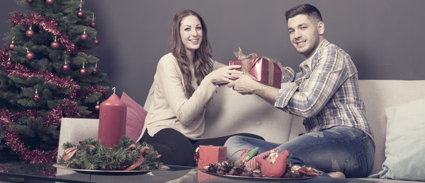 Young couple holding christmas tree at home