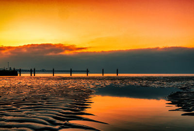 Scenic view of sea against dramatic sky during sunset