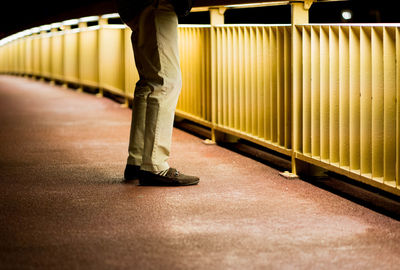 Low section of man walking on illuminated escalator