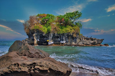 Rock formation on beach against sky
