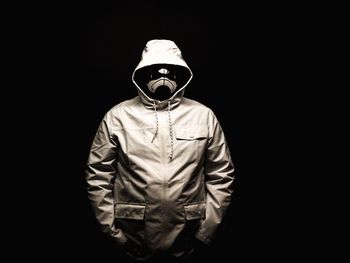 Portrait of man standing against black background