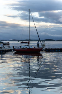 Sailboats moored in marina at sunset