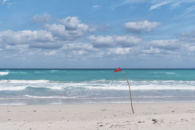 Red flag on sandy beach of atlantic ocean, varadero, cuba. danger sign, swimming is prohibited.