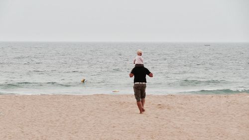 Full length of man standing on beach against sky