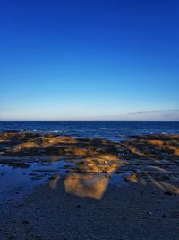 Scenic view of sea against clear blue sky