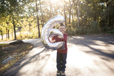 Young elementary age boy holding balloon in afternoon light