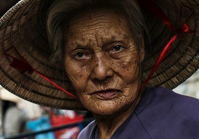 Close-up portrait of senior woman wearing asian style conical hat