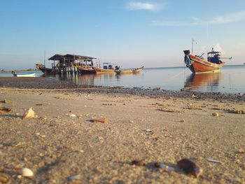 Boats moored on beach against sky