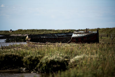 Abandoned boats on field against sky