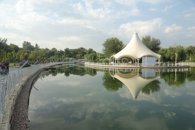 Reflection of bridge and trees in lake against sky