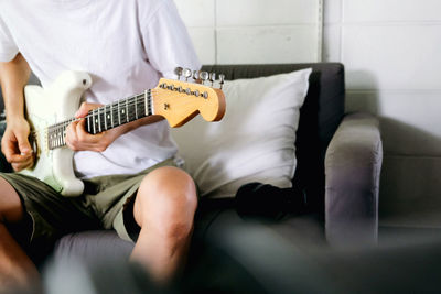 Midsection of man playing guitar