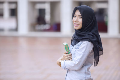 Portrait of woman holding kuran while standing in mosque