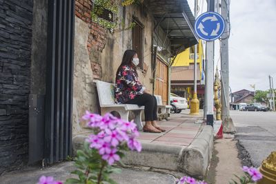 Full length of woman sitting on bench outdoors