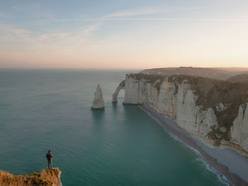 Rock formations by sea against sky during sunset