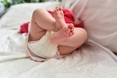 Low section of baby lying on bed