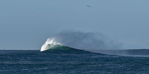 Wave splashing in sea against sky