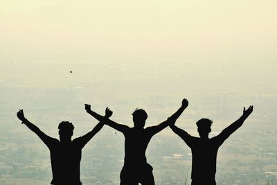 Silhouette people with arms raised in background