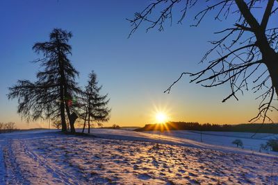 Scenic view of snow covered field against sky at sunset