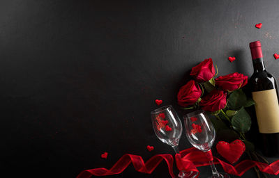 High angle view of red roses on table against black background
