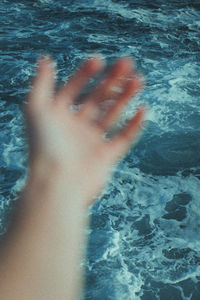 Close-up of human hand at sea