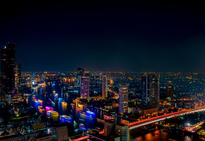 High angle view of illuminated buildings and cruise ship on large lake against sky at night