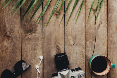 Flat lay travel concept, photo camera, cup of coffee, eyeglasses and earphones, palm leaf