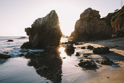 Rocks on beach against clear sky