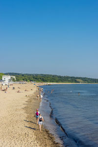 People on beach against clear sky