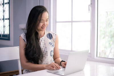 Young woman using mobile phone while sitting on table