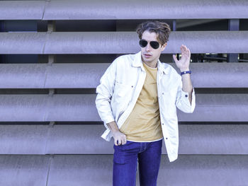 Confident man in casual clothes and sunglasses standing against metal striped wall of garage