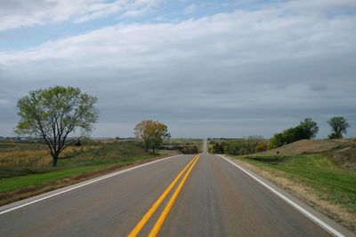 Road by trees against sky