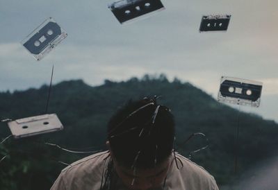 Close-up of young man amidst audio cassettes in mid-air