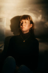 Portrait of a serious young woman sitting against wall