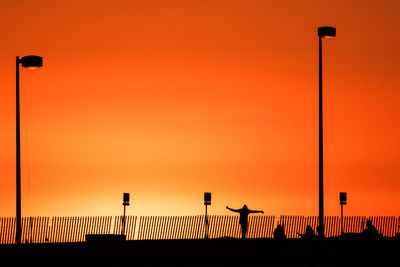 Silhouette man against orange sky