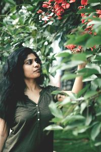 Woman touching red flowers blooming on tree