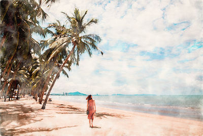 Rear view of woman on beach against sky