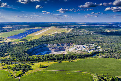 Top view of a stone, granite quarry. beautiful forest, blue sky, clouds. river flows.