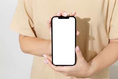 Midsection of woman using mobile phone against white background