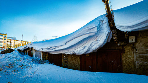 An unusual snow drift on the roofs of a small building looks mesmerizing, spring 2021